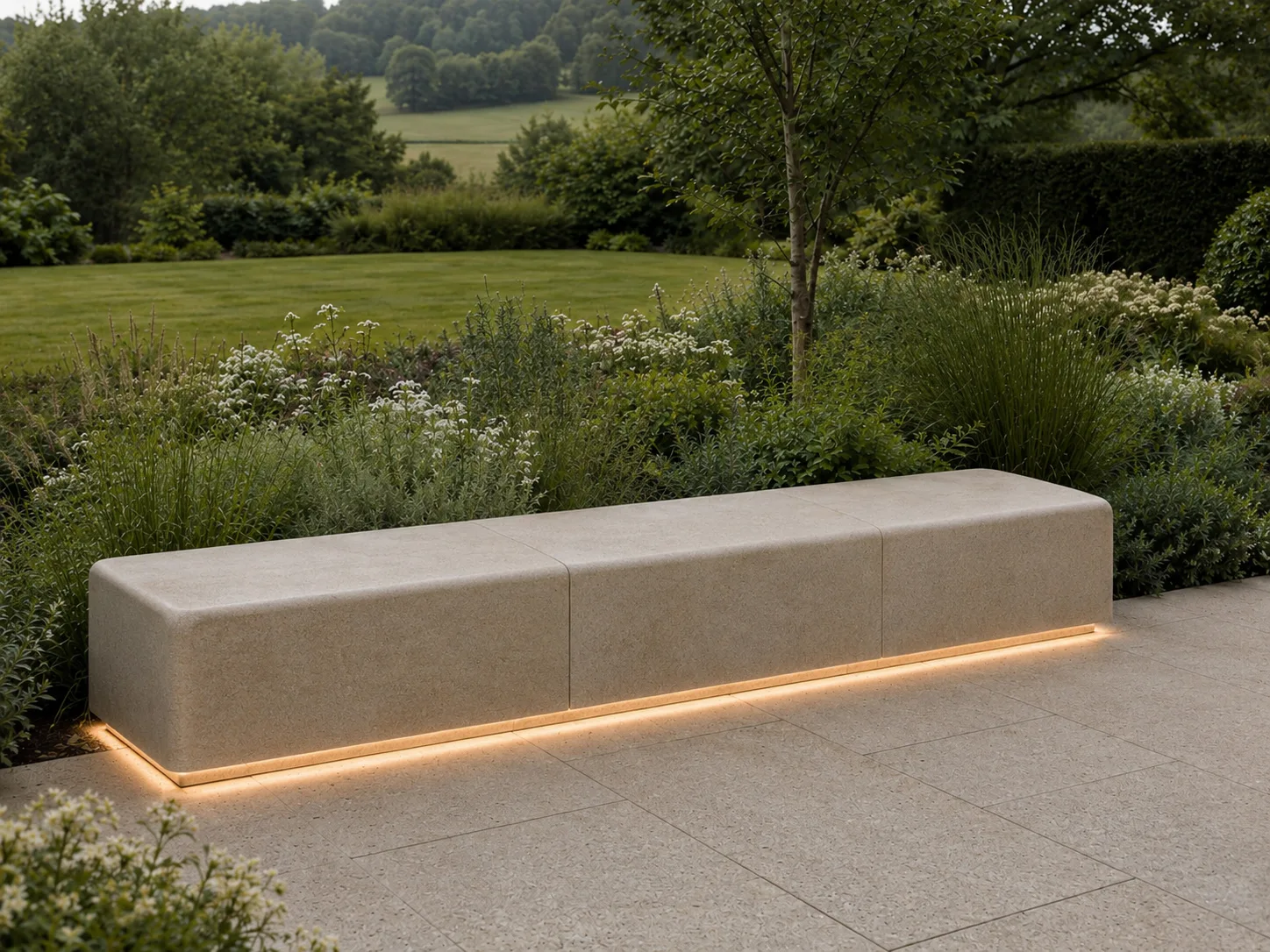 A stone bench with soft lighting underneath, set in a landscaped garden with greenery and distant hills.